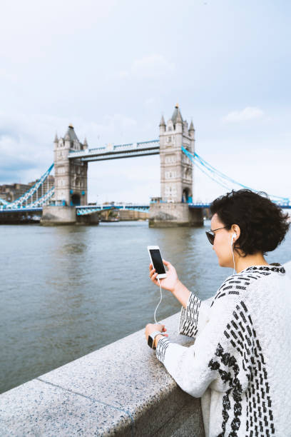 istock Young woman using mobile phone, Tower Bridge at the background 990639710