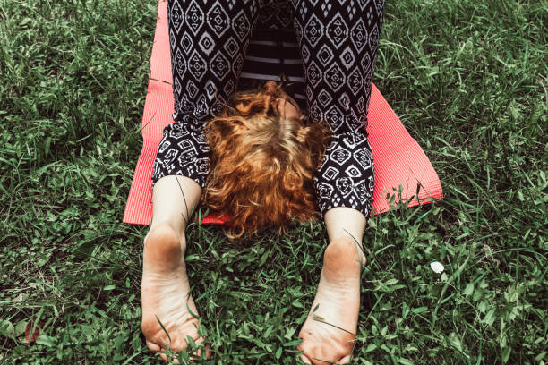 One woman, orange hair girl outdoors in park, doing yoga.