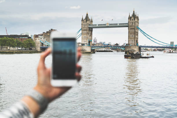istock Young woman using mobile phone, photographing Tower Bridge 990642622