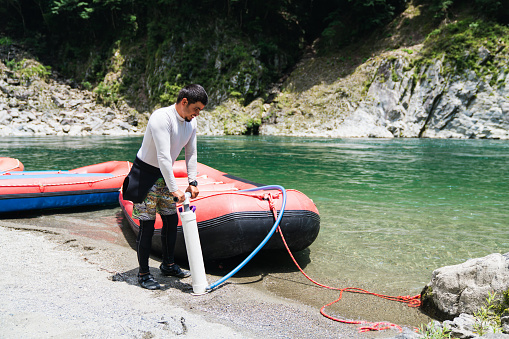 A male adventure guide inflating a raft to go white water river rafting