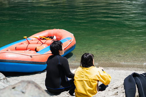 Mid adult couple taking a lunch break on a beach while river rafting