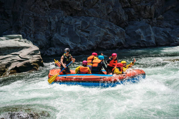 Group of men and women white water river rafting in a forested valley in Japan.