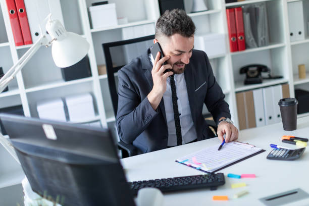 istock A man is sitting in the office at the table, talking on the phone and working with documents. 990659166