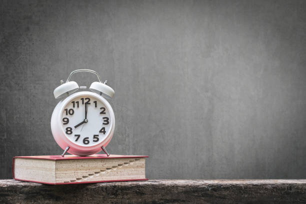 istock Back to school education concept with clock on book on black chalkboard 990660238