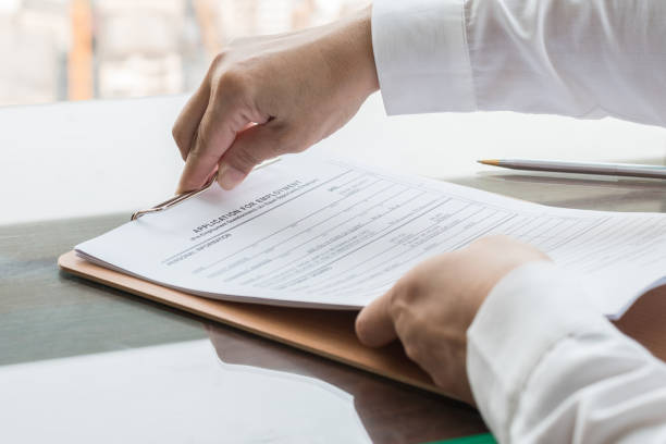 istock Applicant filing in company application form document applying for job, or registering claim for health insurance 990660390