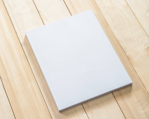 istock Blank book cover mockup template with page front side on white surface on wood table 990660402
