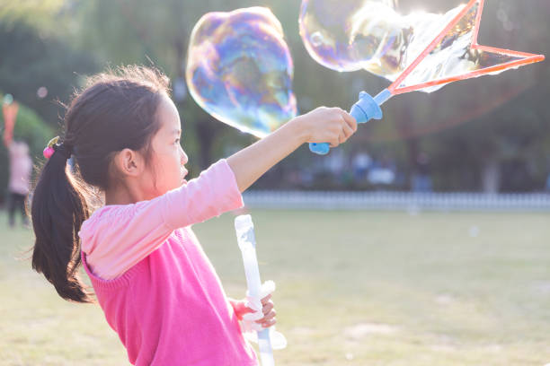 istock Happy girl playing soap bubbles in park. 990663782