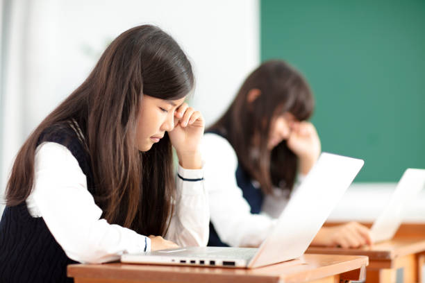 istock tired teenagers student studying with laptop in classroom 990711124