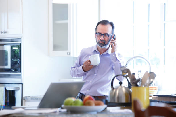 istock Hispanic Man Stands In His Kitchen And Talks On His Mobile Phone 990719794