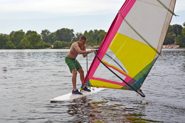istock man stands on the Board in the water, windsurfing 990727210