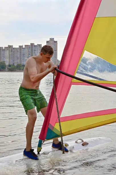 man stands on the Board in the water windsurfing