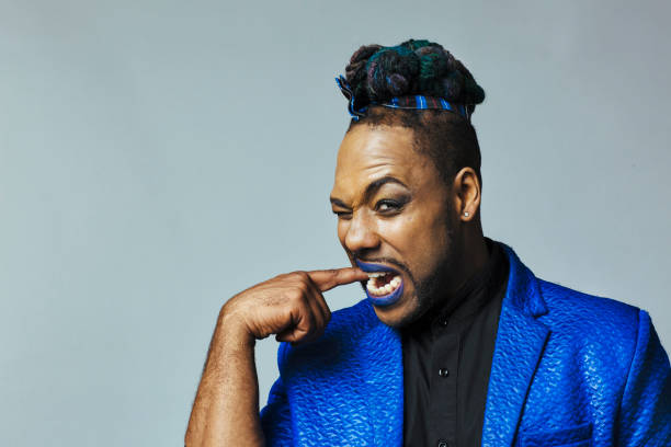 Man with blue lips and jacket biting his finger Man with blue lips, hair and jacket biting his finger, isolated on studio background offbeat stock pictures, royalty-free photos & images