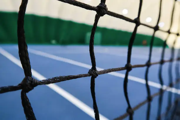 Close-up view of tennis court through the net