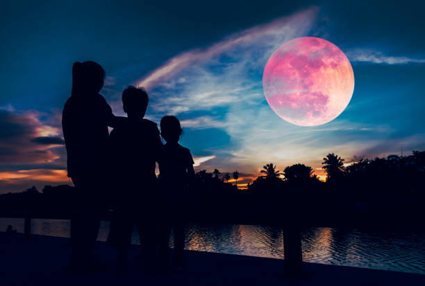 silhouette of mother with children looking at red super moon on sky. - kd imagens e fotografias de stock