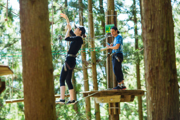 istock Young woman on a rope bridge in a forest obstacle course 990790996