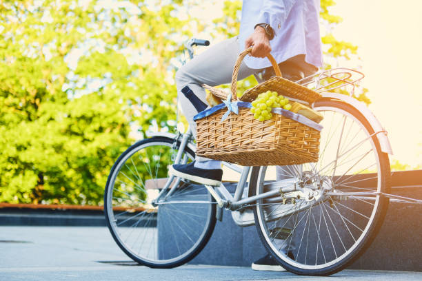 mann auf ein city-bike hält picknick-korb. - fahrradkorb stock-fotos und bilder