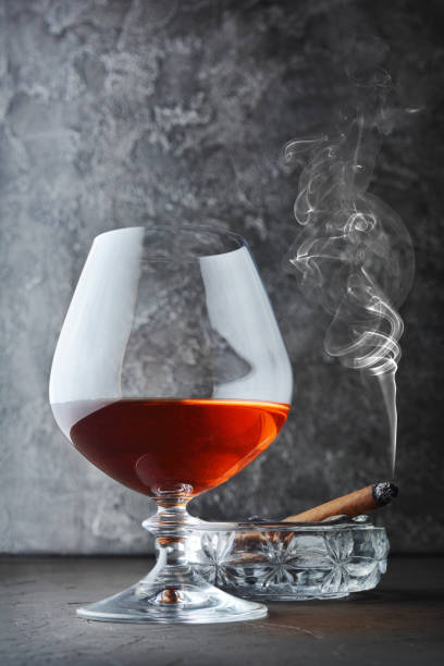 istock Strong alcoholic drink cognac in sniffer glass with smoking cigar in crystal ashtray 990822032