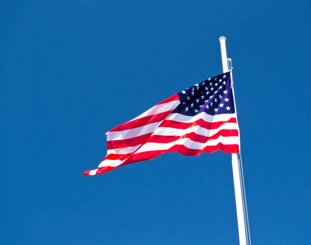 istock usa flag waving in the wind with blue sky as background. 990822054