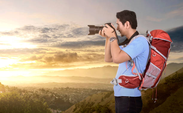 istock Side view of asian photographer man with backpack taking a photos 990844400