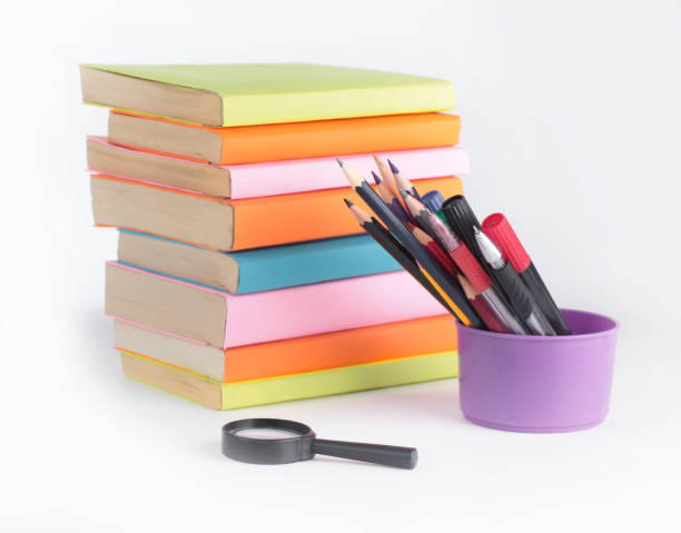 istock magnifying glass, pencils and stack of books on white background 990849724