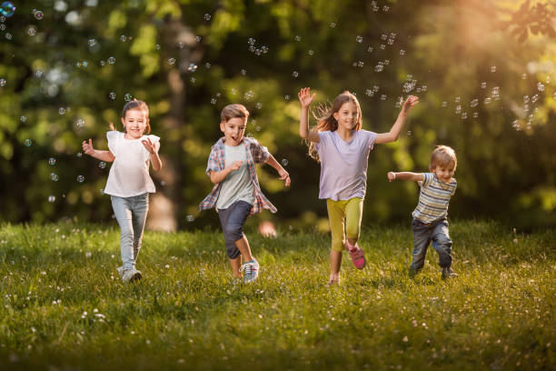 istock Happy kids having fun while running among bubbles in springtime. 990853602