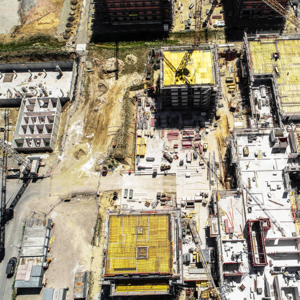 istock Vertical view from a great height of a square building shell covered with yellow sealing mats, aerial photo, nadir 990856558
