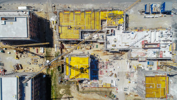 istock Vertical view from a great height of a square building shell covered with yellow sealing mats, aerial photo, nadir 990856652