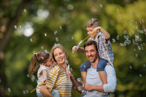 jeune famille heureux s’amuser au cours de la journée de printemps dans la nature. - bubble wand outdoors little boys mother photos et images de collection