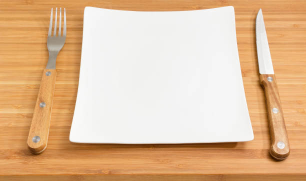 istock Empty square white dish, fork and knife with wooden handles 990860440