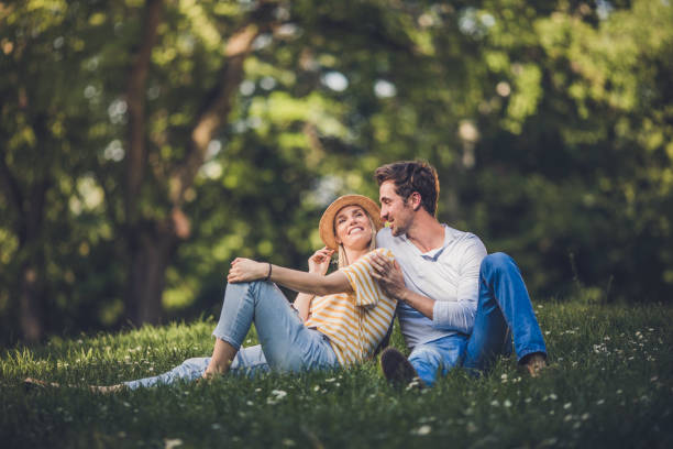 Happy couple relaxing in grass during spring day and talking to each other.