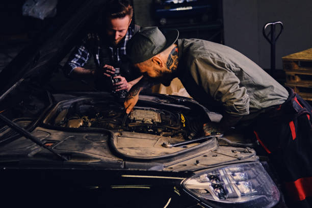 istock Two mechanics fixing car's engine in a garage. 990872722