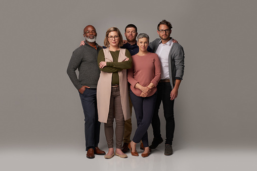 Studio shot of a group of people posing together against a gray background
