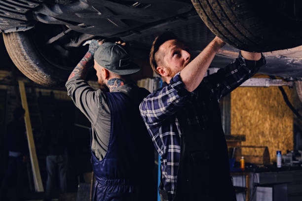 istock Two mechanics balancing car's wheels in a workshop. 990885522