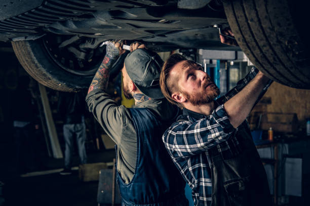 istock Two mechanics balancing car's wheels in a workshop. 990888260