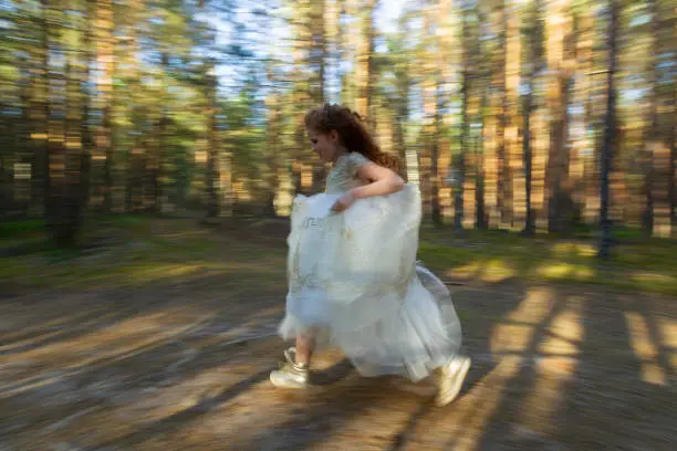 Little princess wallks in an evening dress in a summer forest, natural light