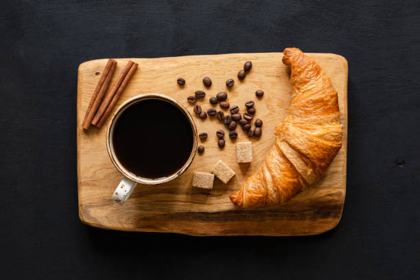 istock Coffee and croissant on wooden board, top view 990893868