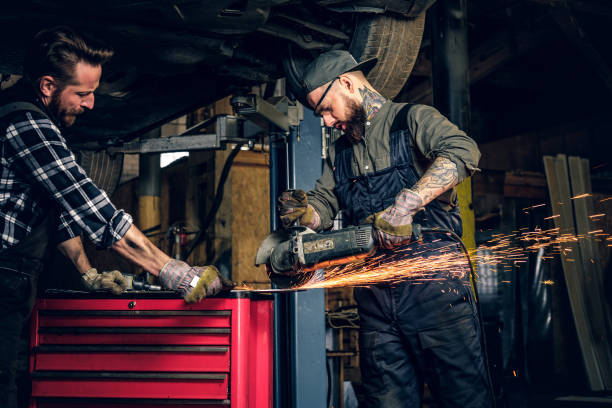 istock Two b mechanics working with an angle grinder in a garage. 990897476