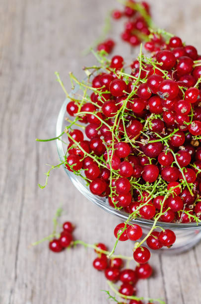 istock Ripe red currant on wooden background. 990898858