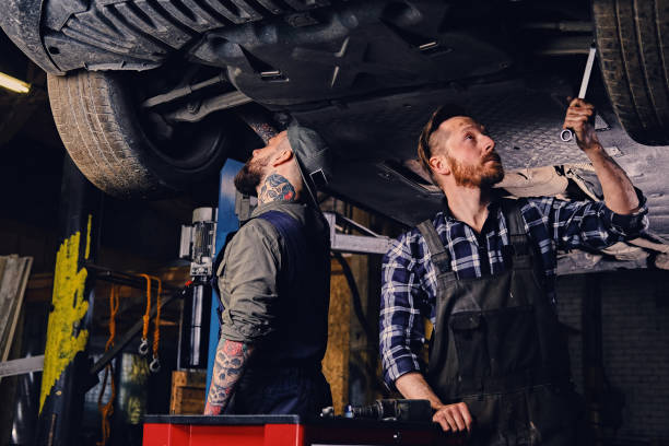 istock Two mechanics balancing car's wheels in a workshop. 990898960