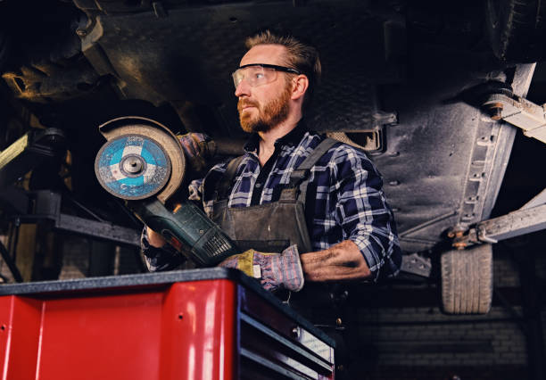 istock Mechanic in protective googles holds angle grinder. 990899112