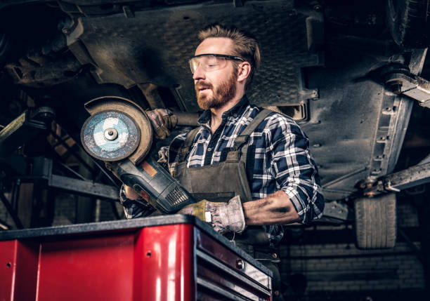 istock Mechanic in protective googles holds angle grinder. 990901722