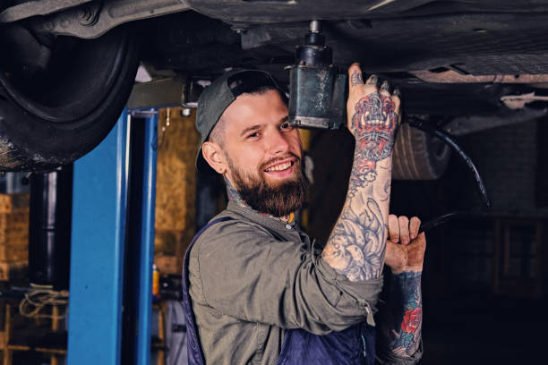 istock Bearded  mechanic working with the car's chassis in a workshop. 990906974