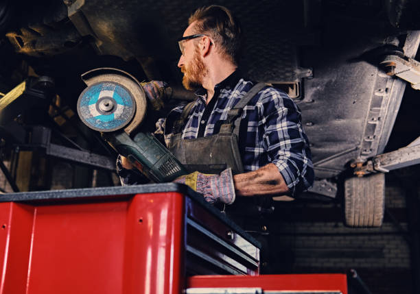 istock Mechanic in protective googles holds angle grinder. 990907354