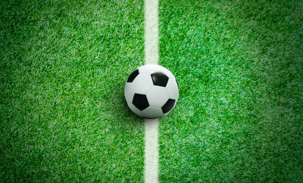 istock Soccer ball on green grass in stadium with copy space 990909484