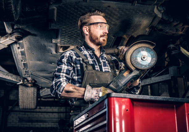 istock Mechanic in protective googles holds angle grinder. 990910572