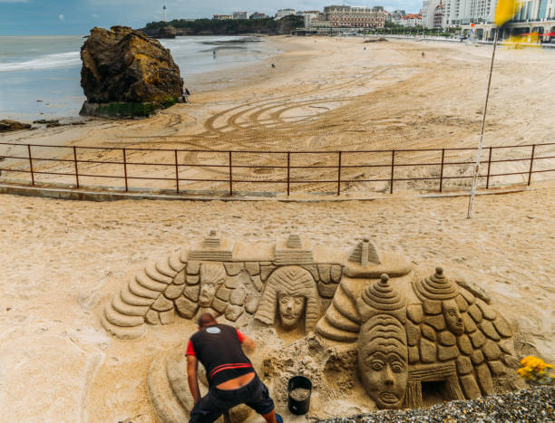 Man builds an elaborate sand castle at the Grande Plage beach in Biarritz, Aquitaine, France Biarritz, France - June 14th, 2018: Man builds an elaborate sand castle at the Grande Plage beach in Biarritz, Aquitaine, France sandcastle structure stock pictures, royalty-free photos & images