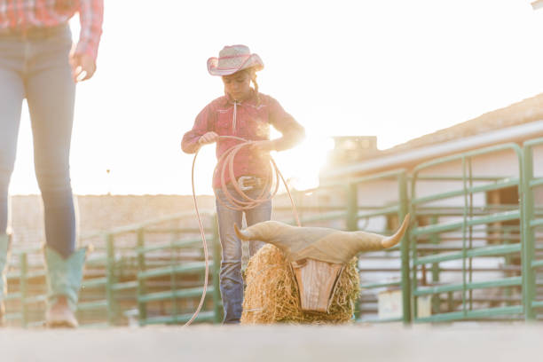 istock Young cowgirl rolling up lasso after practice 990918116