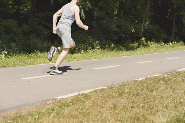 istock Young man jogging on treadmill in park, copy space 990924738