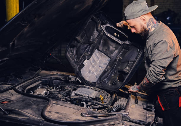 istock Bearded tattooed mechanics near car in a garage. 990940422