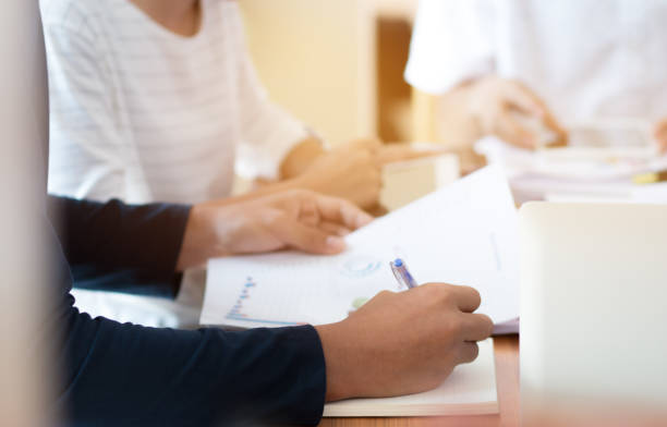 istock Co working team meeting concept: Business people working and studying together use digital tablet laptop computer with document paper in office, discuss finance and marketing solution in offices room 990940872